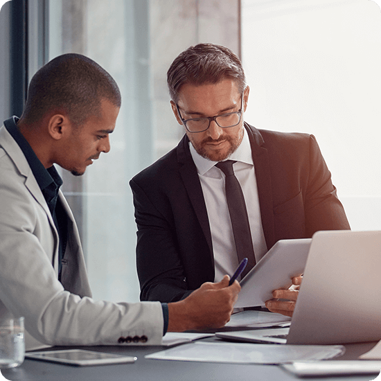 Two professionals talking over a tablet with papers on a table
