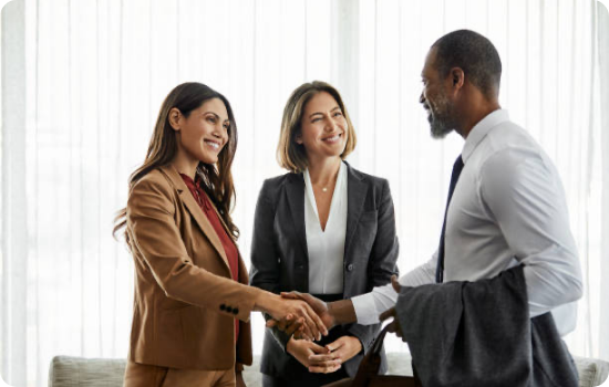 Three business professionals shaking hands in a modern office setting, symbolizing a successful partnership or agreement.